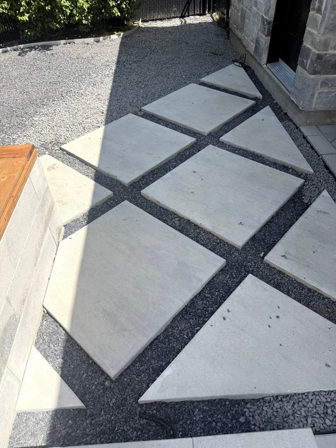Dalles de béton en diagonale posées sur du gravier, avant le gazon synthétique