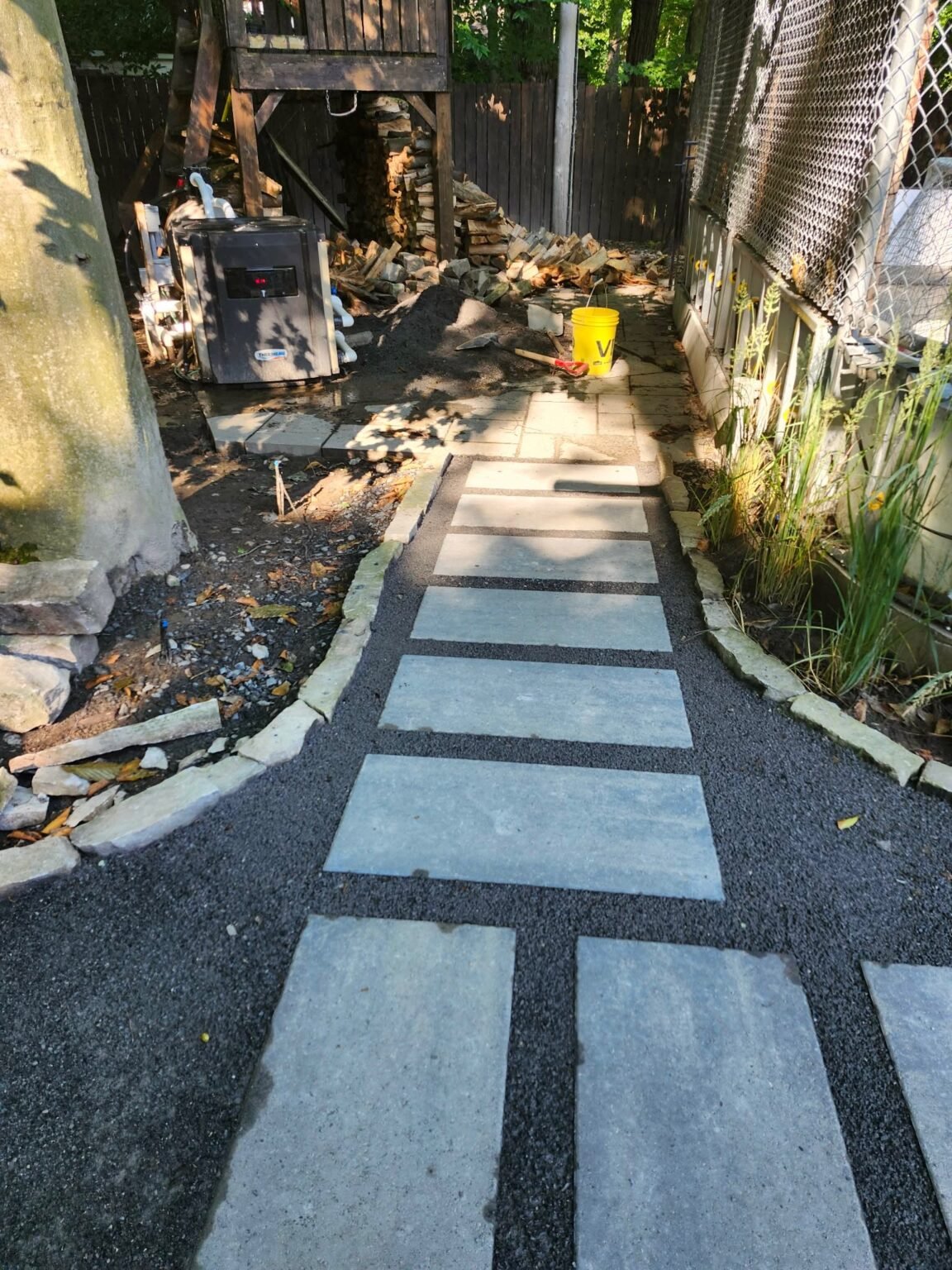 Allée de dalles de béton sur gravier avant l'installation du gazon synthétique