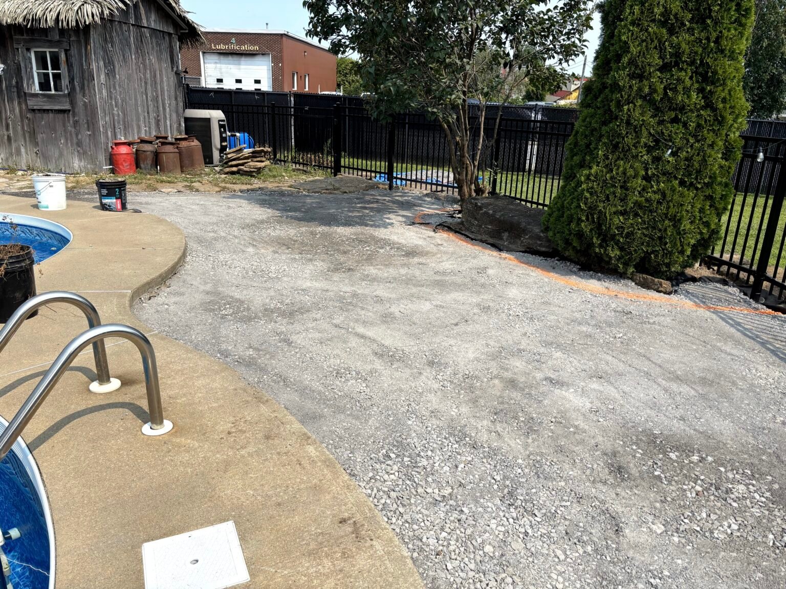 Fondation de pierre concassée autour d'une piscine, tracé orange au sol, avant le gazon